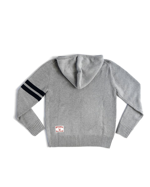The Comp Zip Sweater - Gray/Navy is a light gray cotton-blend sweater with ribbed cuffs and hem, two black left sleeve stripes, a YKK Vislon zipper, and a small white patch with red text near the back hem.