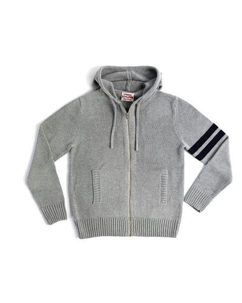 The Comp Zip Sweater - Gray/Navy is a light gray hoodie with navy stripes on the left sleeve, YKK Vislon zipper, hood, drawstrings, and two front pockets. Crafted from soft cotton-blend sweater fabric for comfort.