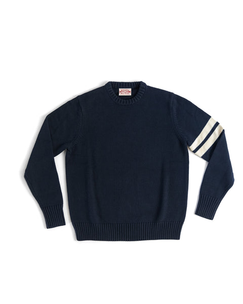 The Comp Stripe Sweater - Navy/Bone features ribbed cuffs and hem, two white stripes on the left sleeve, and is crafted from soft 100% cotton for lasting comfort, shown laid flat on a white background.