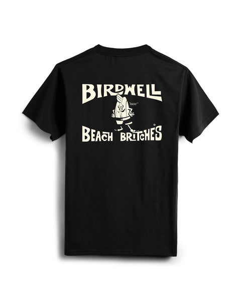 The License Plate T-Shirt - Black/White features “Birdwell Beach Britches” and a cartoon character in cream graphics on the back. Made in the USA from 100% vintage cotton, the character wears shorts and gives a thumbs up.