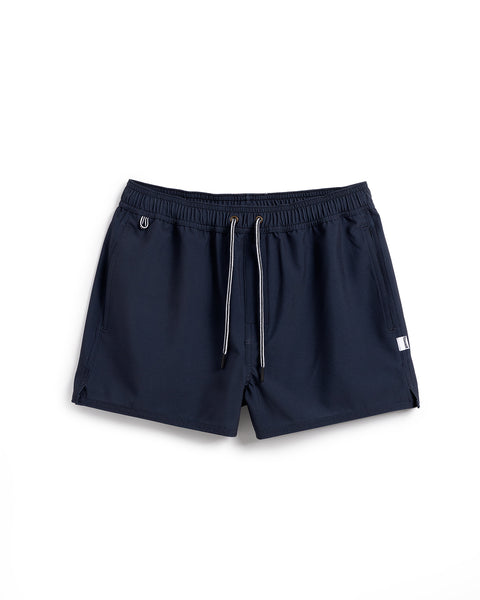 The Women's Wright Short - Navy features an elastic waistband, drawstring, side pockets, and a small white tag on the left leg. Made from recycled polyester, these navy leisure shorts are shown on a white background.