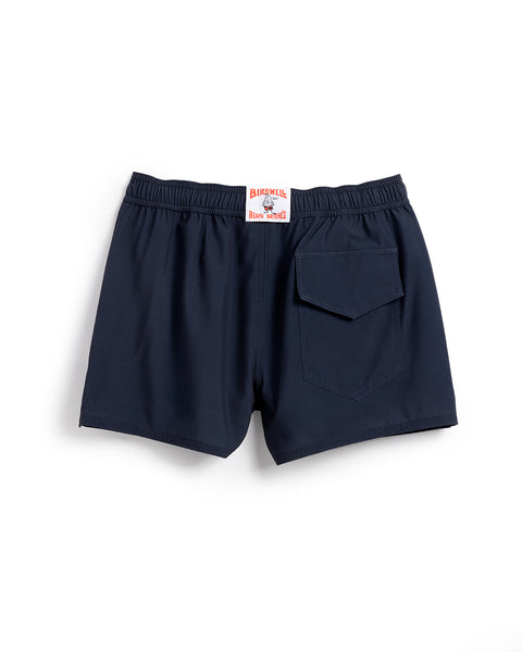 The Women's Wright Short - Navy is made from recycled polyester, featuring an elastic waistband, single flap back pocket, and a white label with red text and graphic above the waistband. Shorts are displayed flat on a white background.