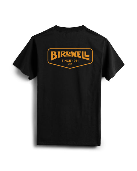 The Service T-Shirt - Black is a heavyweight tee featuring an orange and yellow Birdwell Since 1961 USA logo printed on the upper back.